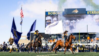 Bobcat riders and Champ lead the flags through the smoke