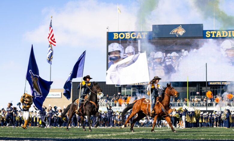 Bobcat riders and Champ lead the flags through the smoke