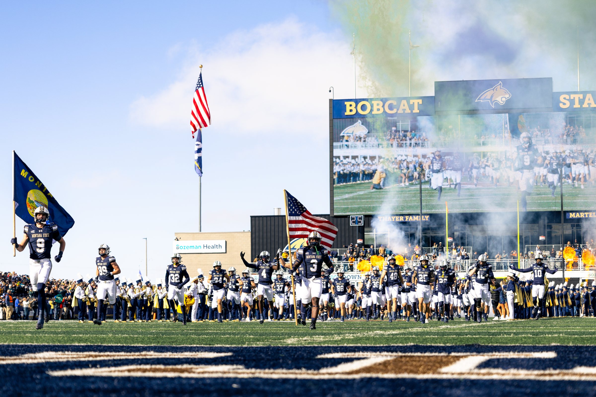 The Bobcats charge onto the field behind the Montana flag