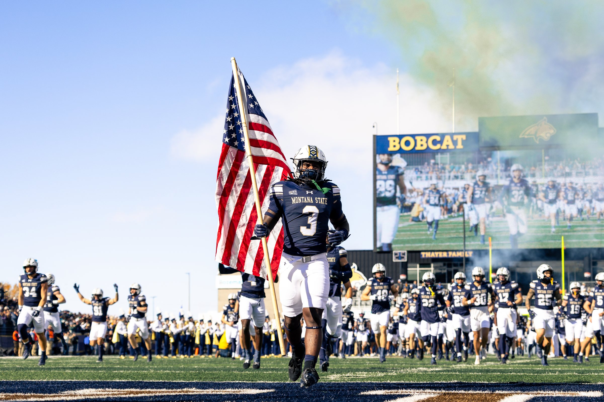 Jared White carries the American flag onto the field