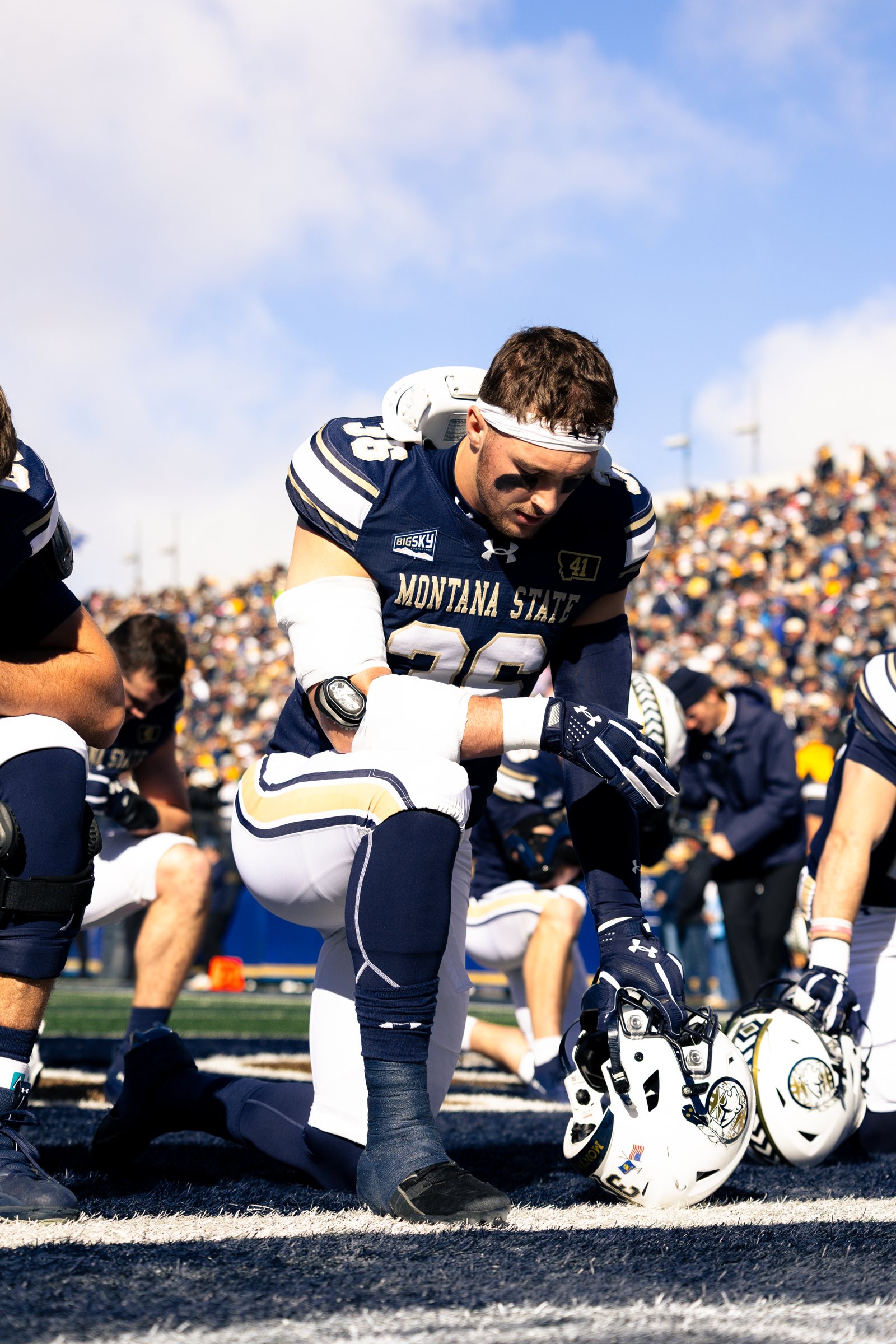 Zac Crews kneels in prayer before kickoff